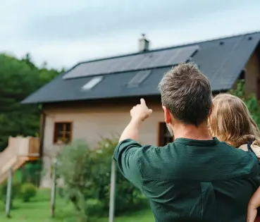 Placas solares en una casa, padre e hija las observan.