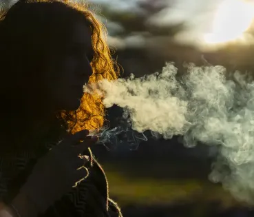 Mujer fumando en un espacio natural.