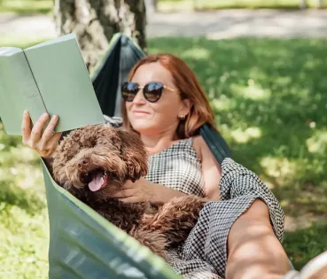 Mujer leyendo en un jardín en la sombra, con precaución a la exposición solar.